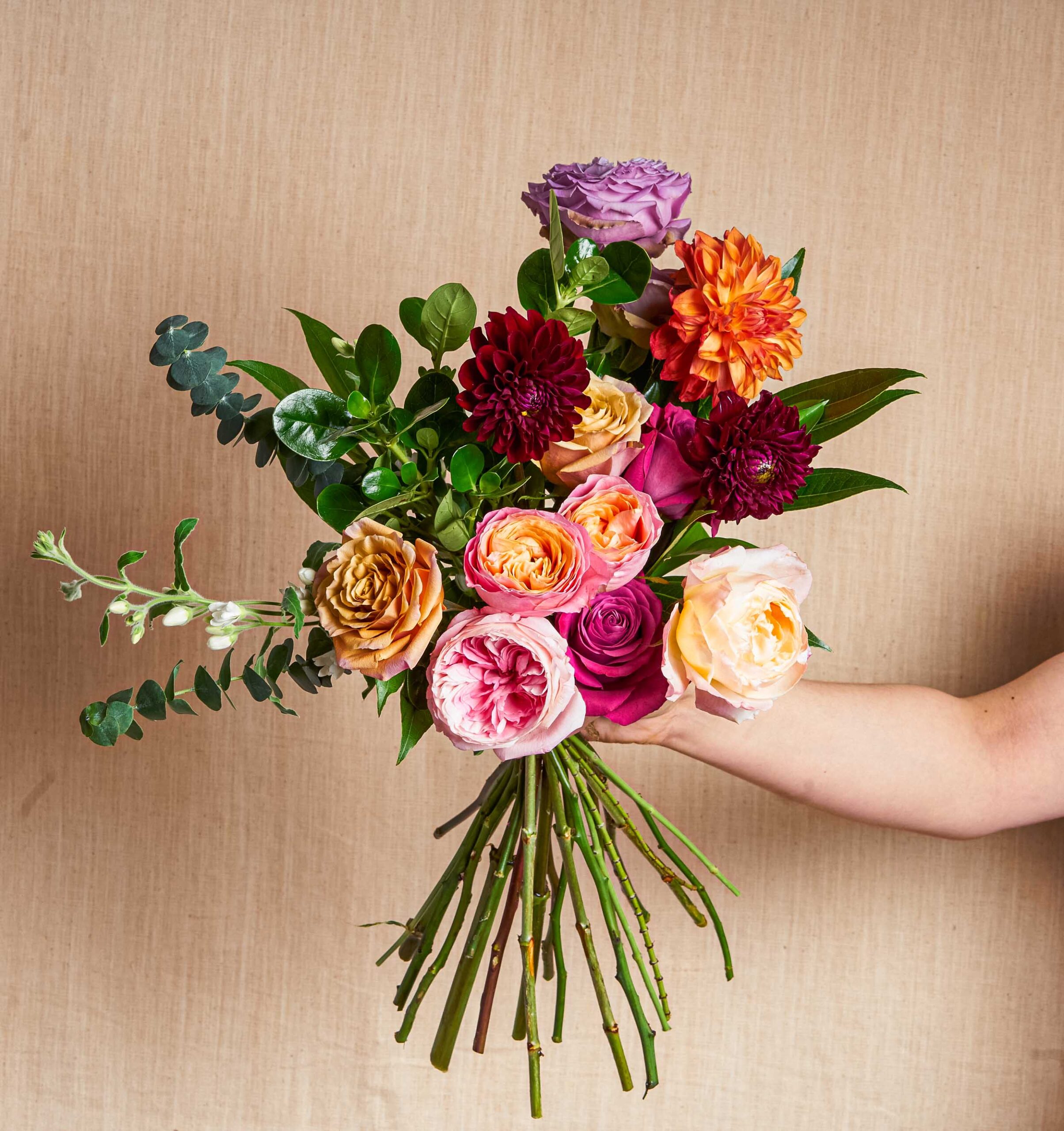 Colorful roses and dahlias arrangement in a hand
