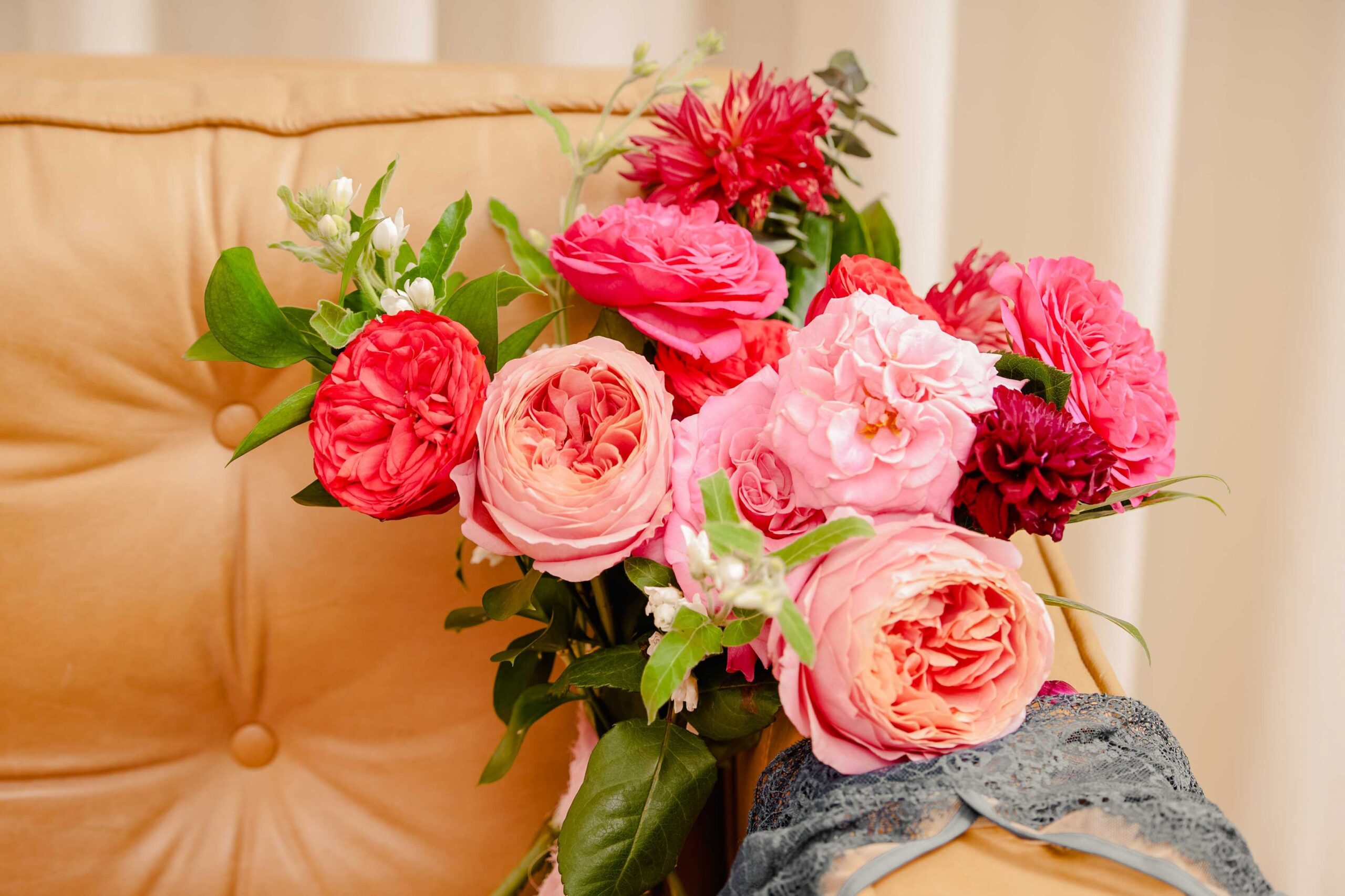 Pink and red roses and dahlias on a couch